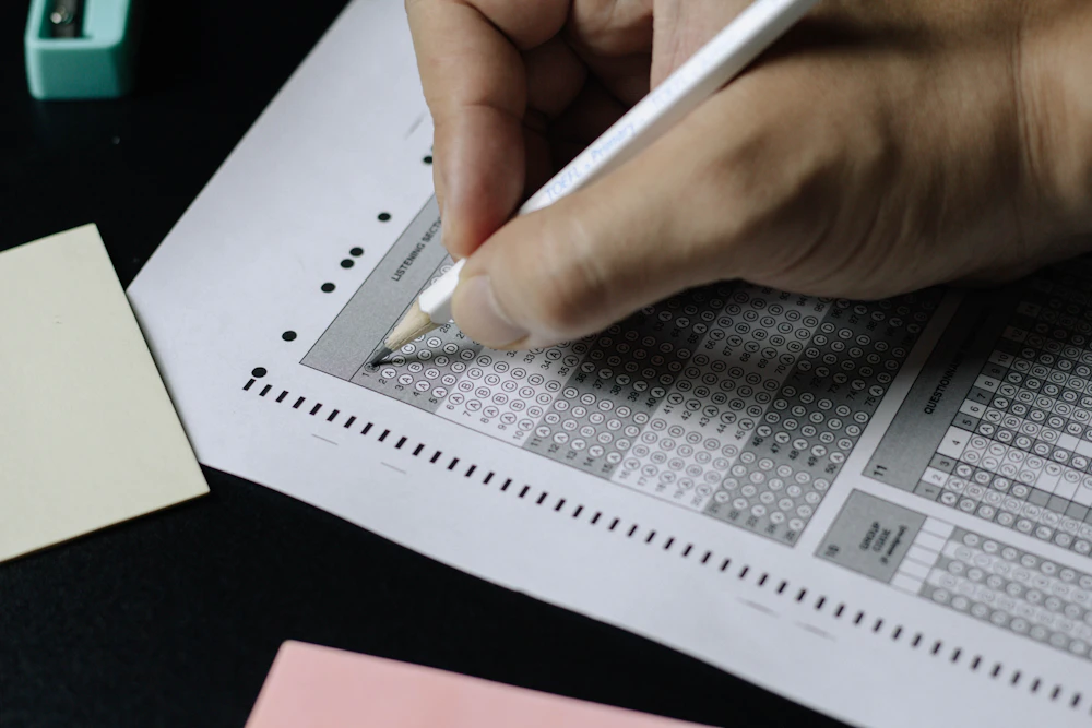 Une main remplit une grille de réponses au crayon